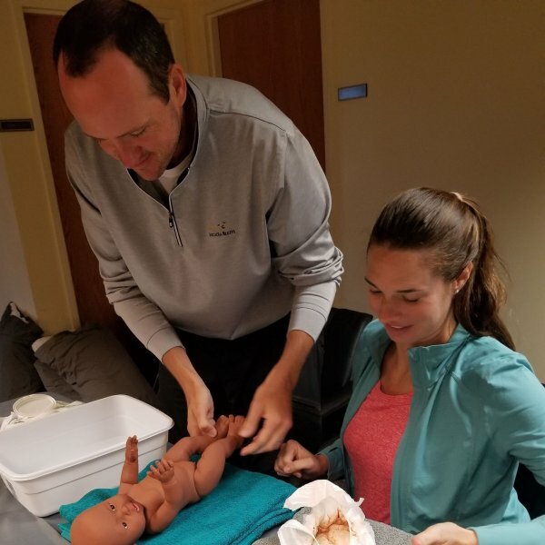 man and woman changing fake baby's diaper